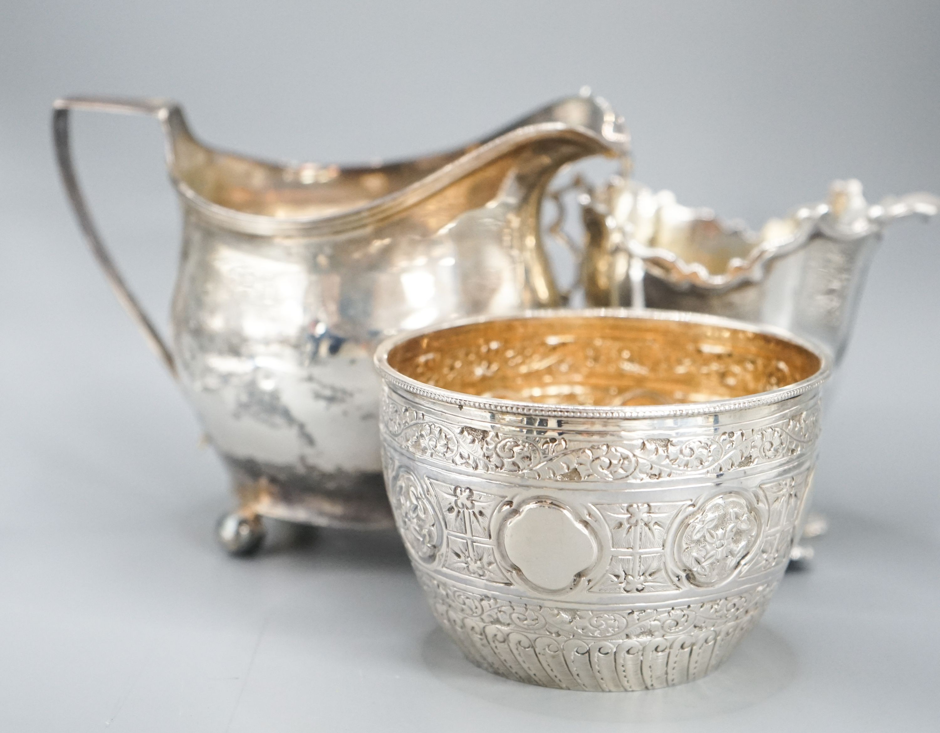A Victorian repousse silver sugar bowl, a George III silver cream jug and a later silver cream jug